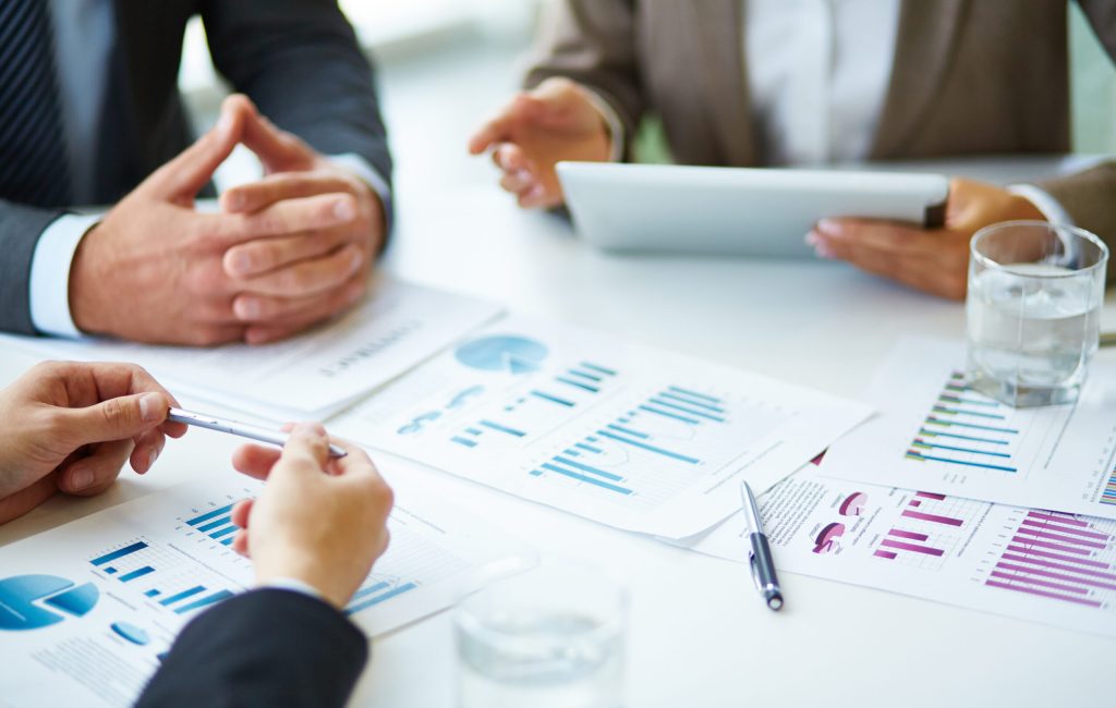 Image of business documents, pen and glasses on workplace during meeting of partners