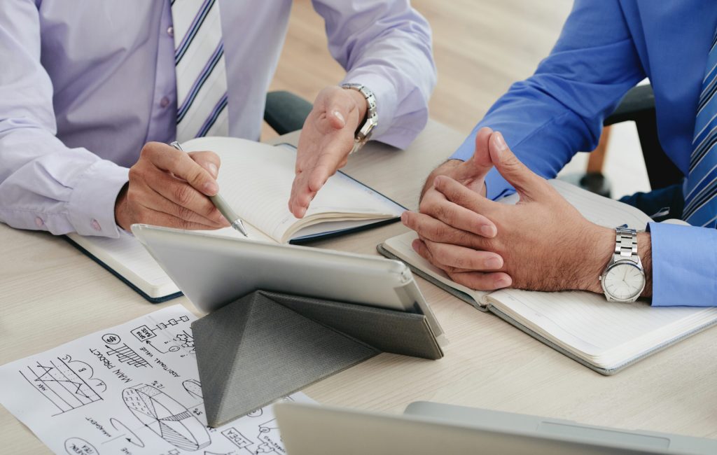 Close-up image of coworkers discussing data on tablet computer screen