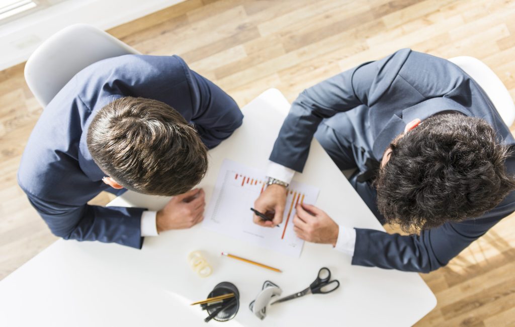 overhead-view-businessmen-working-company-financial-report-white-desk